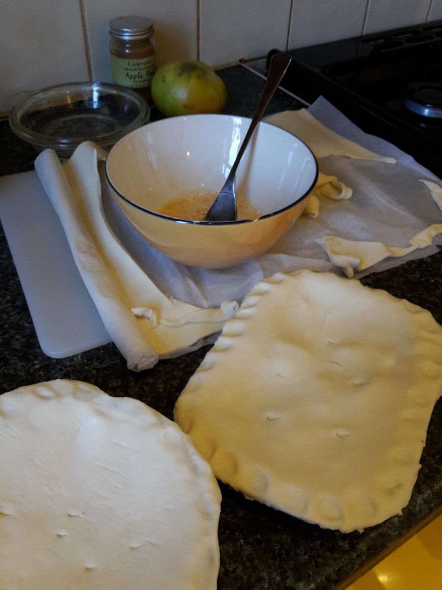 Two small pies ready to be baked in the oven after they are smeared with egg yolk